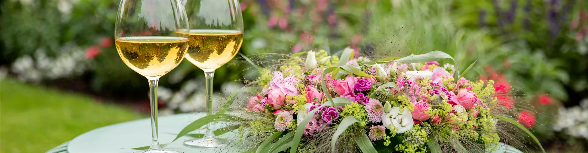 Blumenkranz und Weinschorle auf Gartentisch